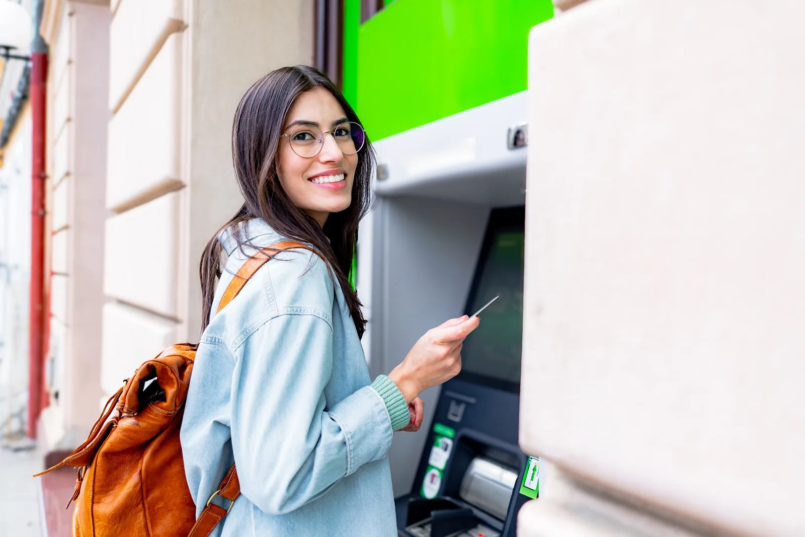 Transport CU member holding her credit union debit card at an ATM